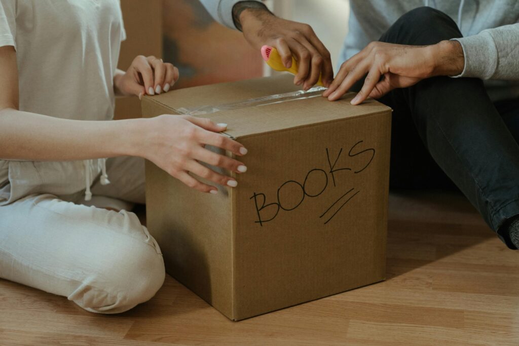A couple unpacking books in their new home, focusing on teamwork and domestic life.
