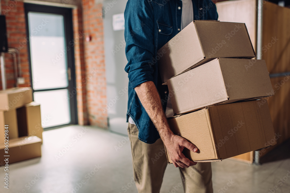 selective focus of businessman holding boxes and moving in new office